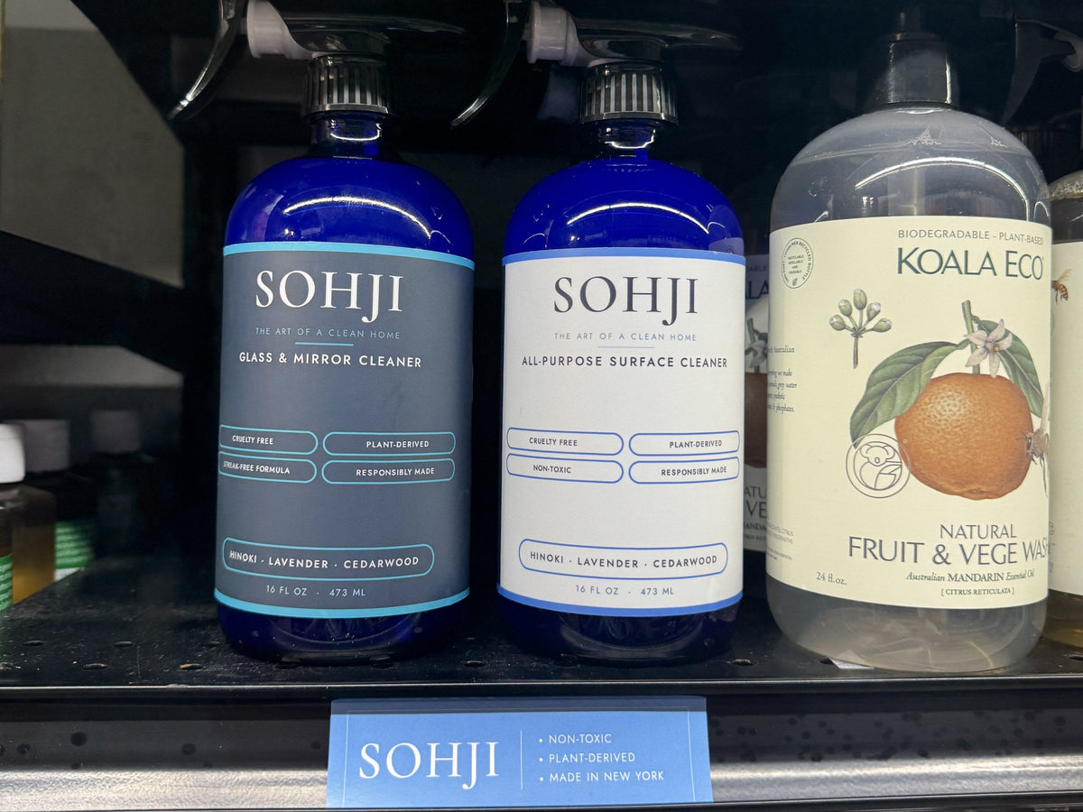 SOHJI Glass & Mirror and All-Purpose cleaners on a NYC store shelf above a blue SOHJI shelf strip